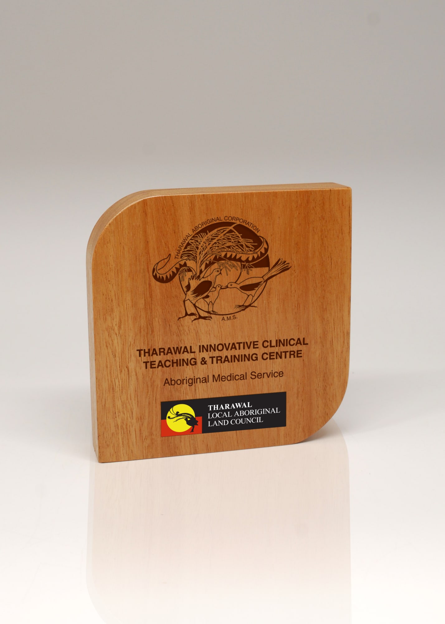 A wooden trophy with a curved edge, featuring a design and a logo. The colour is a light brown wood finish. Australian Select Grade Blackbutt Form Trophy - Image 1