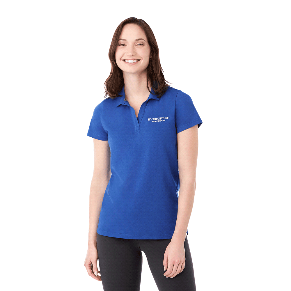 A woman wearing a blue short sleeve polo shirt with a logo. The top has a classic collar and a fitted design. Somoto Eco Short Sleeve Polo - Womens - Image 1