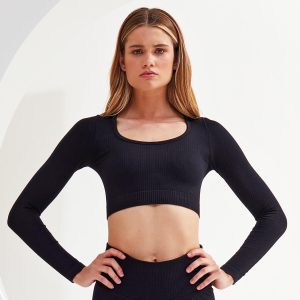 A ribbed, seamless black crop top with long sleeves and a scoop neckline. It features a fitted design and has a logo.