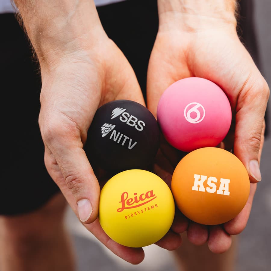 Four colourful high bounce balls in hand: black, pink, orange, and yellow, each with different logos. Wiz High Bounce Ball - Image 1