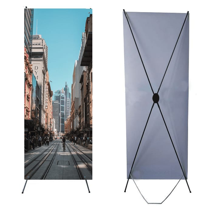 An X banner featuring a city street scene, set against a light blue background with a sturdy black frame. X Banner / X-Banner - Image 1
