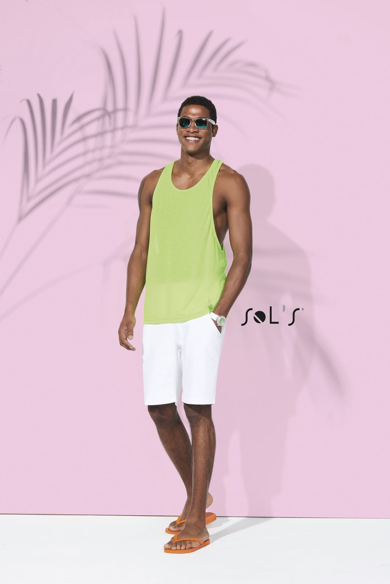 A unisex singlet tank top in bright green, worn by a model in white shorts and sunglasses, with a logo present. Singlet tank top Unisex JAMAICA - Image 1