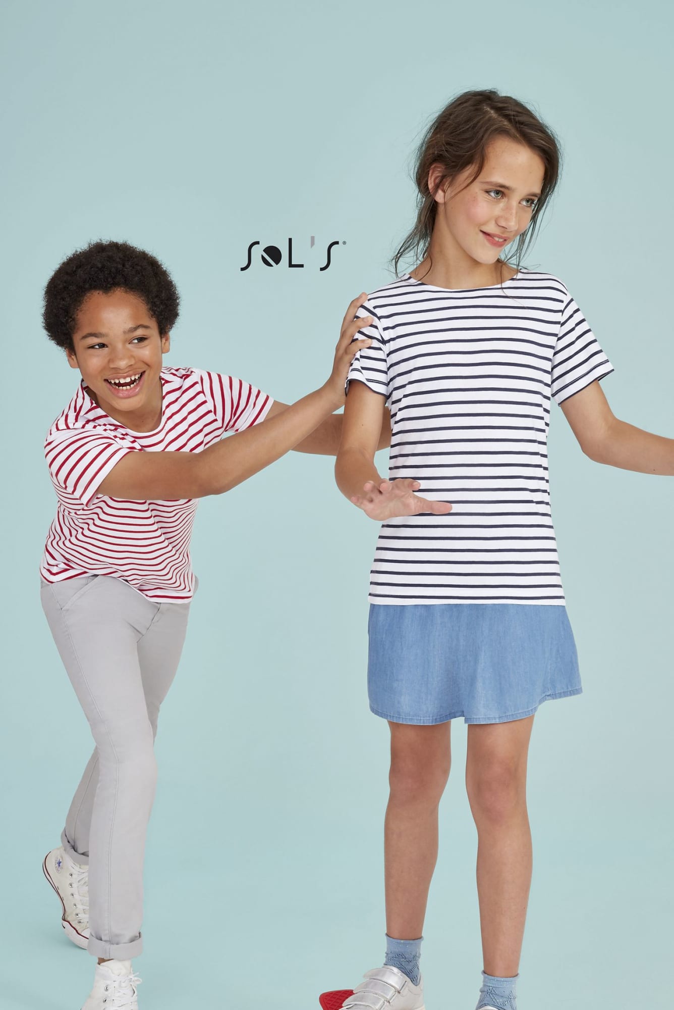 Two kids wearing striped round-neck T-shirts in red and navy blue, standing against a light blue background. T shirt KIDS striped and round neck combed cotton MILES - Image 1
