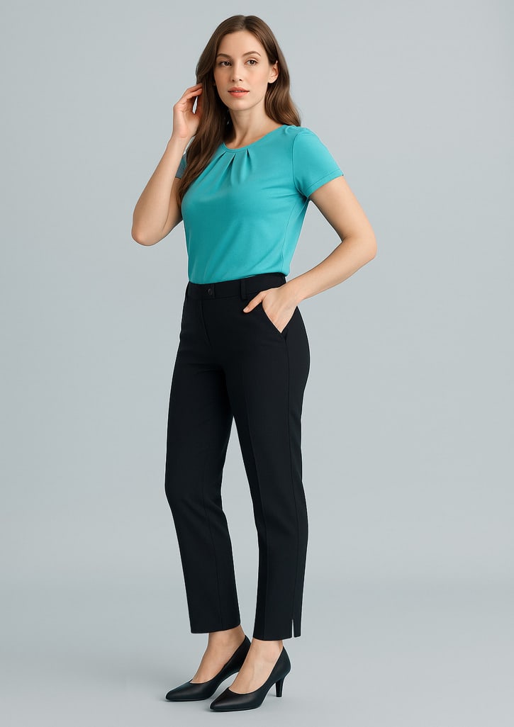 A woman wearing a turquoise top and black slim leg pants, standing against a light grey backdrop. The pants feature pockets and a logo. Womens Cool Stretch Slim Leg Pant - Image 1
