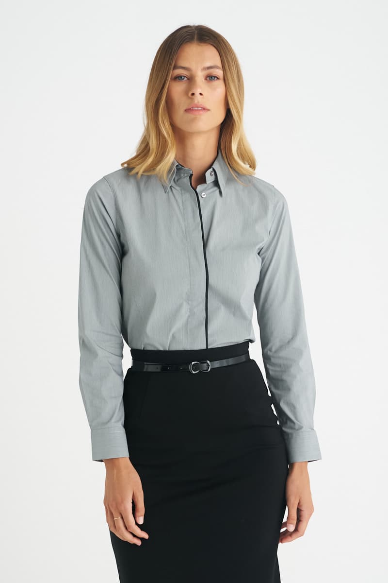 A grey ladies long sleeve button-up shirt worn with a black skirt, featuring a subtle logo. Stella - Ladies Long Sleeve Shirt - Image 1
