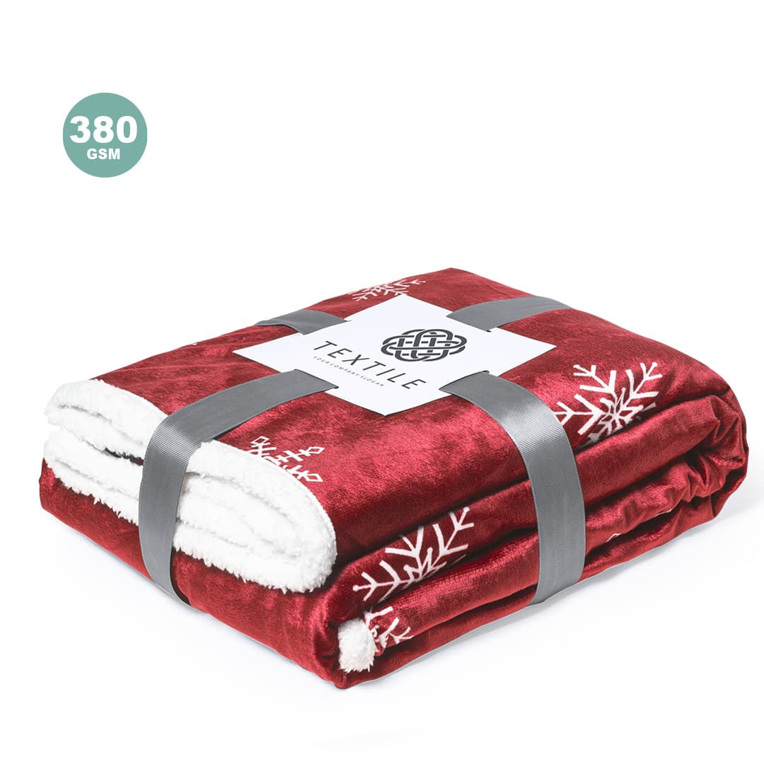 A red blanket with white snowflake patterns, neatly folded and secured with a grey band. It features a logo. Ricord Blanket - Image 1