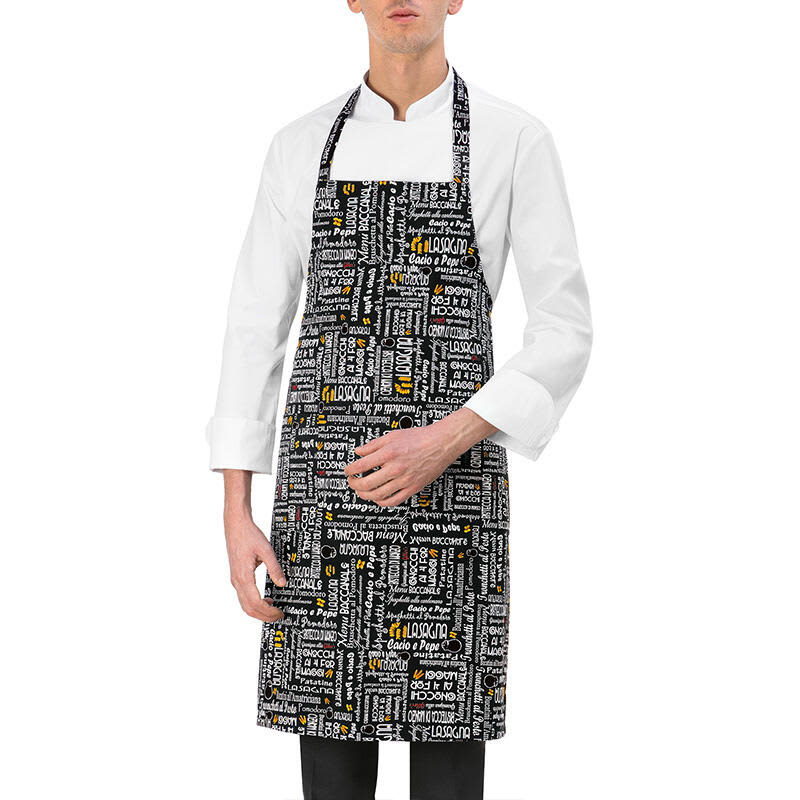 A black apron featuring various white and yellow text designs, worn by a person in a white chef's jacket. Parigi Apron - Image 1