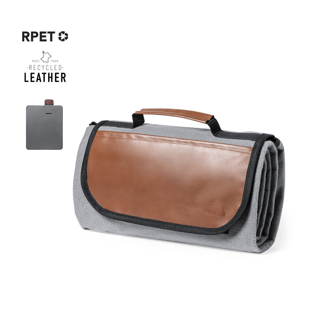 A grey picnic blanket with a brown leather handle and flap, featuring a recycled leather logo. Pirsoy Picnic Blanket - Image 1