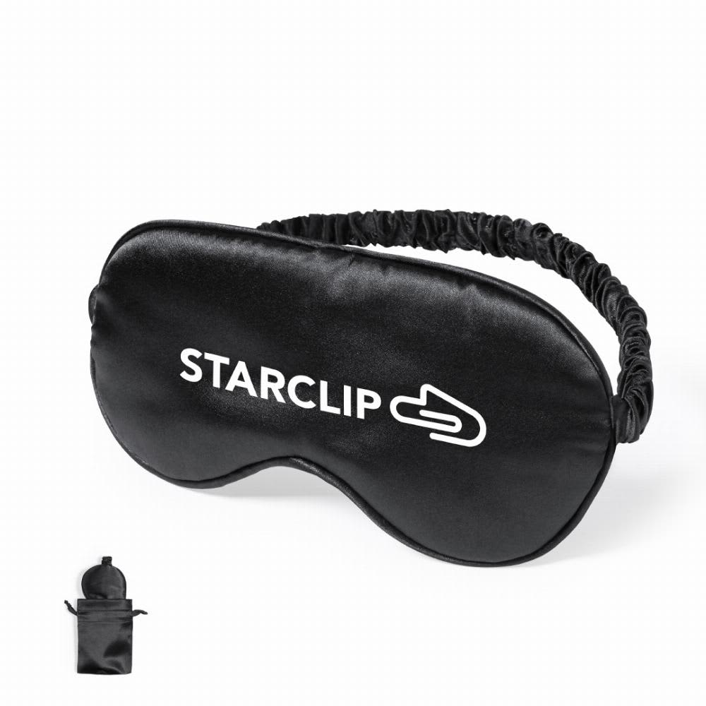 A sleep mask in black fabric with an adjustable strap and a logo. Includes a small pouch for storage. Brenda - Image 1