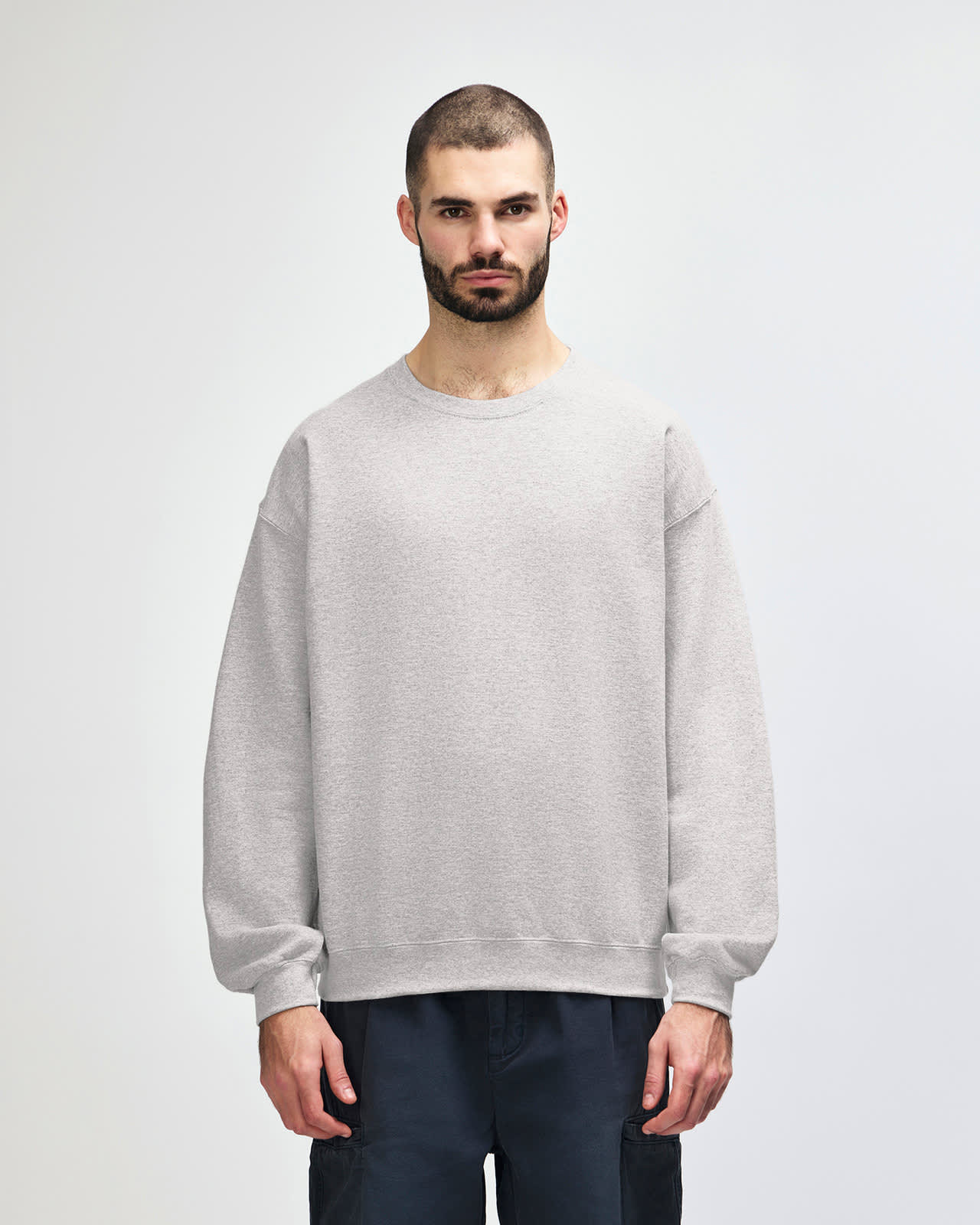 A grey Gildan Heavy Blend adult crewneck sweatshirt displayed on a model, featuring long sleeves and a comfortable fit. Gildan Heavy Blend Adult Crewneck Sweatshirt - Image 1