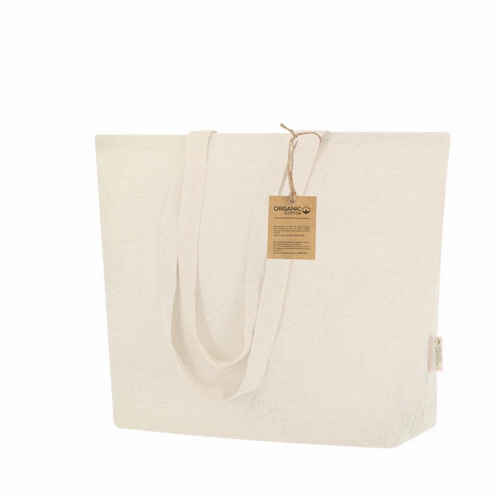 A tote bag in natural tone with long handles, featuring a tag that indicates it is made from organic cotton. Periad - Image 1