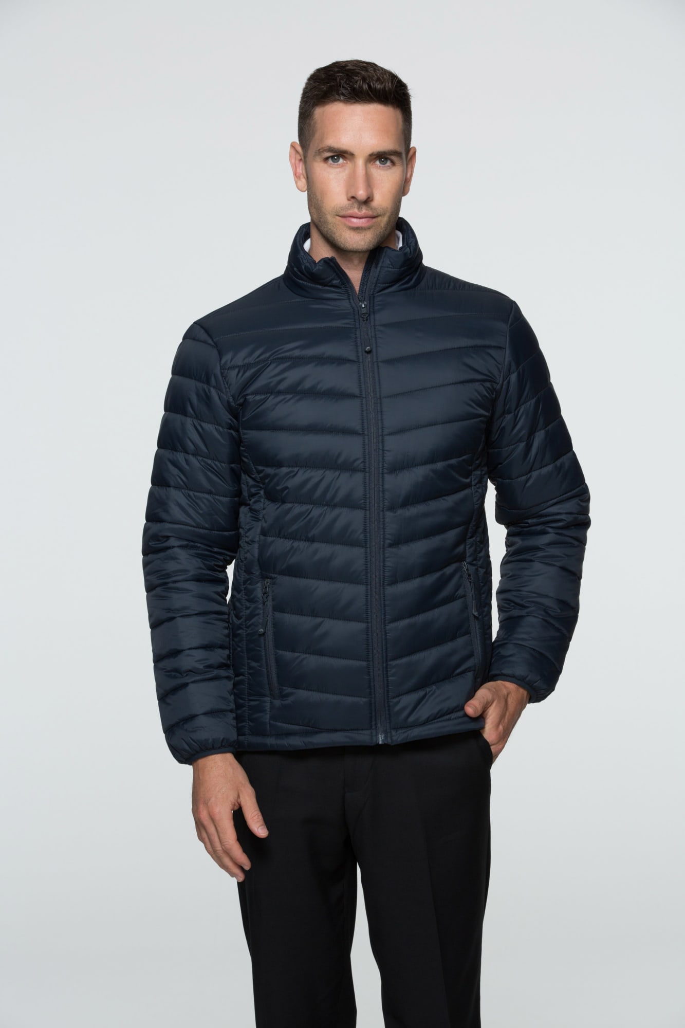 A man wearing a navy blue puffer jacket with a zip front and a stand-up collar, featuring a branding logo. BULLER MENS JACKETS - Image 1