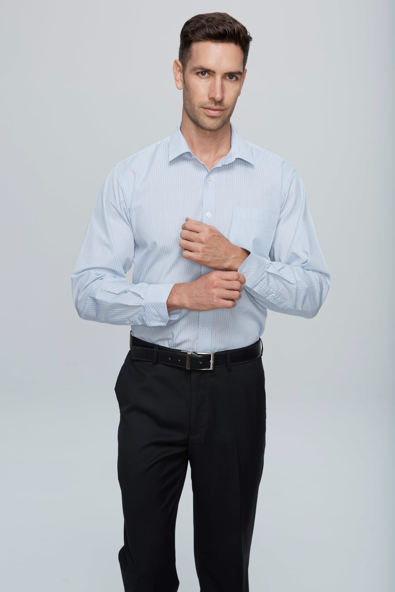 A long sleeve button-up shirt in light blue, featuring a collar and a logo, worn with black trousers. BAYVIEW MENS SHIRT LONG SLEEVE RUNOUT - Image 1