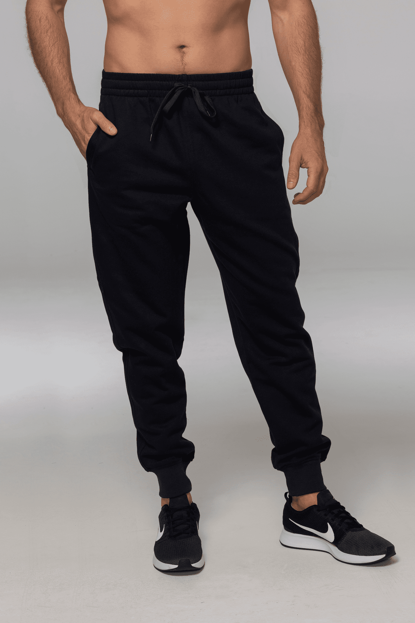 Tapered fleece men's pants in black, featuring an elastic waistband and side pockets. Includes a logo on the garment. TAPERED FLEECE MENS PANTS - Image 1