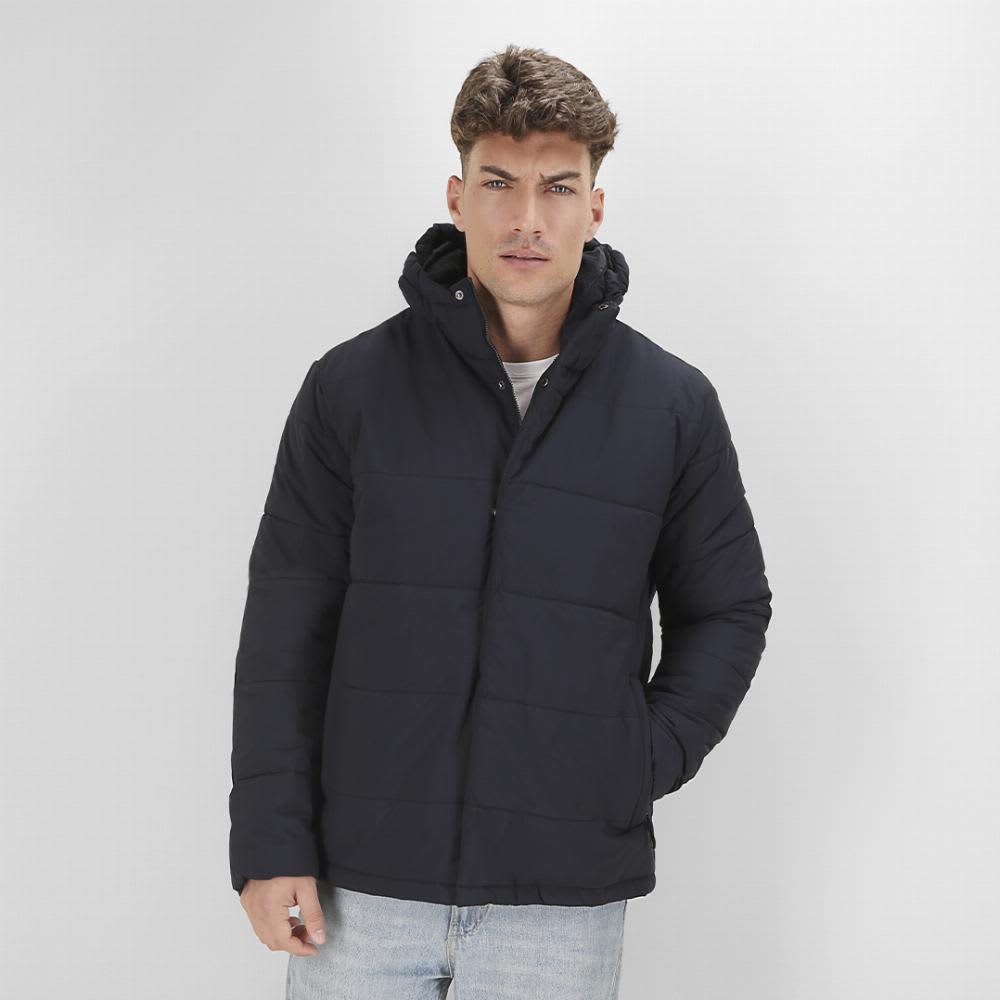 A man wearing a navy puffer jacket with a hood stands against a plain background. Leanor - Image 1