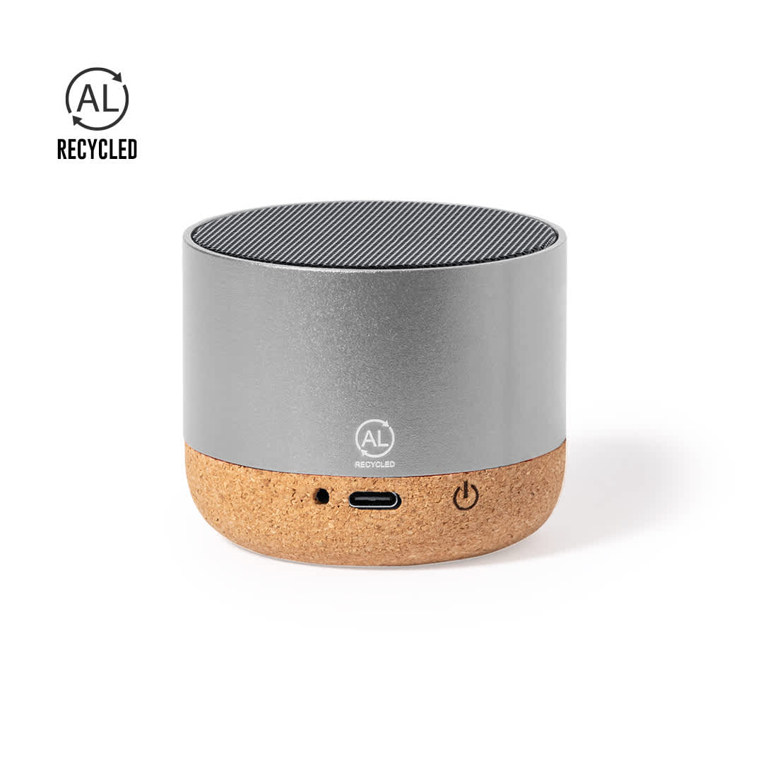 A silver and cork portable speaker featuring a USB-C port and a power button, with a logo on the surface. Moore Speaker - Image 1