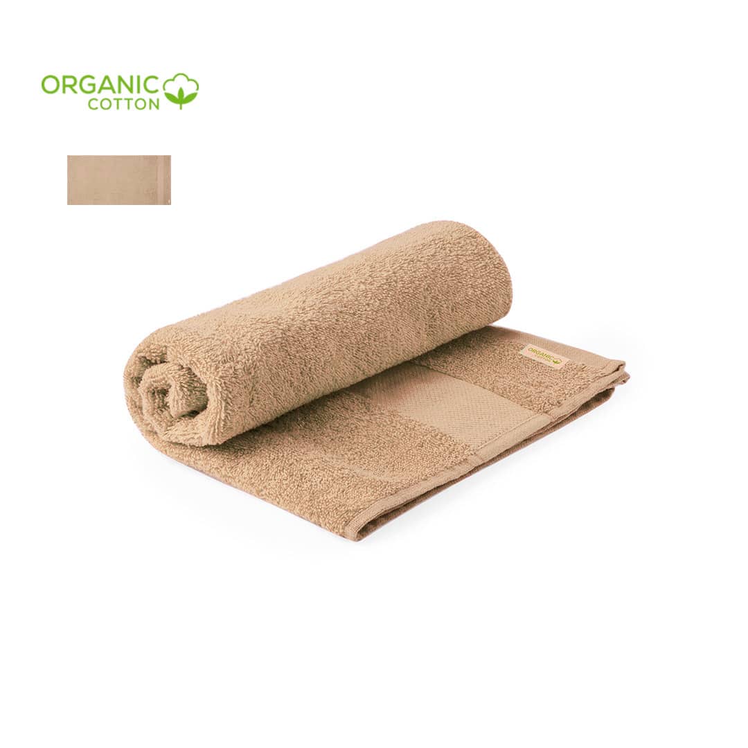 A rolled hand towel in a soft beige colour made of organic cotton, featuring a branded tag. Canoria Towel - Image 1