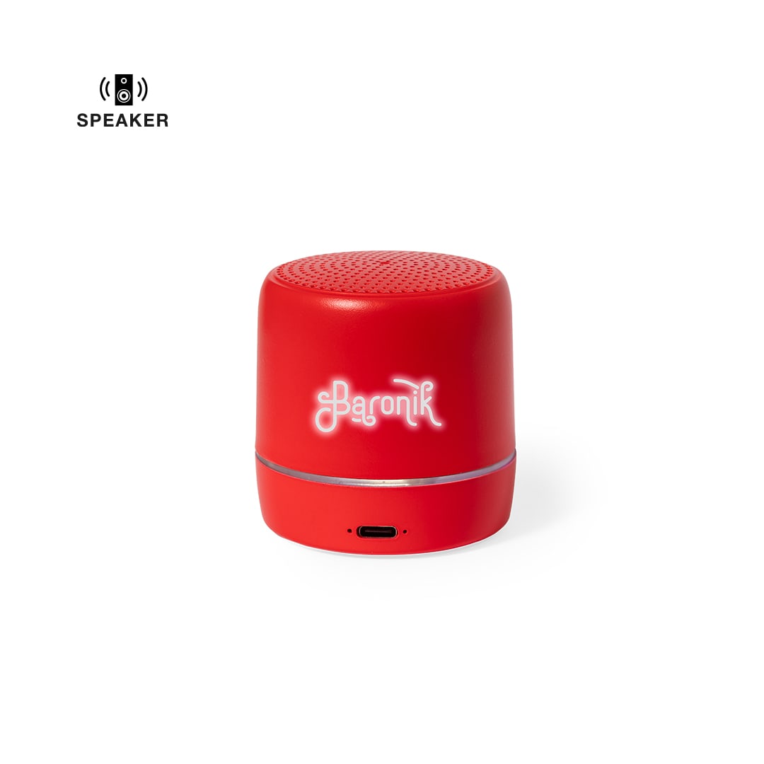 A compact red speaker featuring a circular design and a logo on the front. It has a charging port at the bottom. Kucher Speaker - Image 1