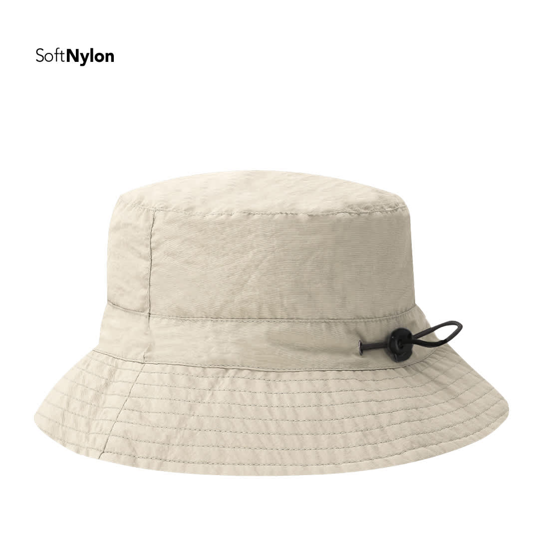 A beige bucket hat made from soft nylon, featuring a drawstring for adjustment and a logo. Dagger Hat - Image 1
