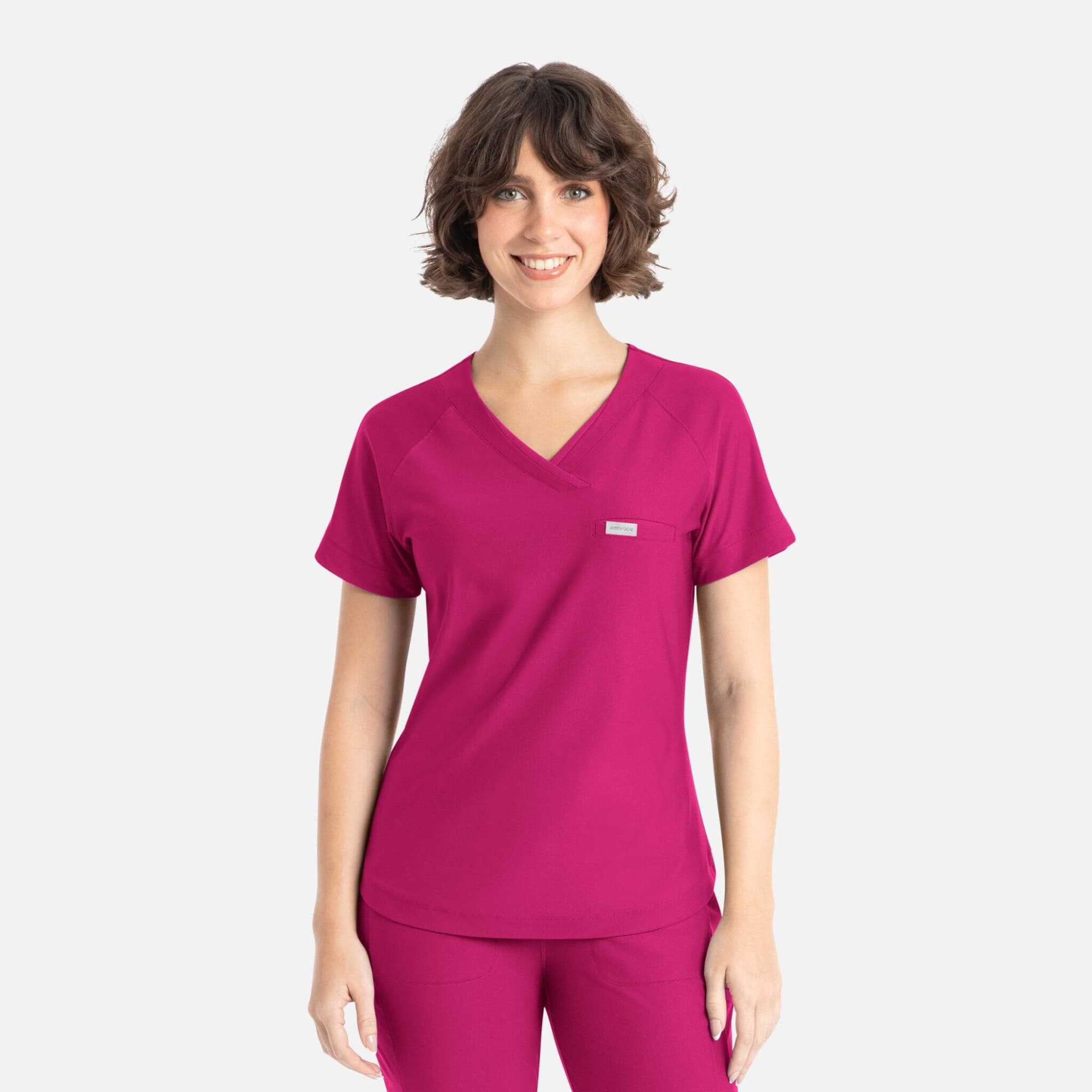 A pink Y-neck top featuring short sleeves and a logo on the chest. Embrace Luna Tuckable Y-Neck Top - Image 1