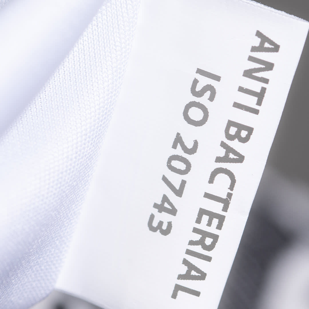 A close-up of a white fabric label highlighting "Anti Bacterial" and "ISO 20743." The background is blurred. Maxcron Antibacterial Bag - Image 1