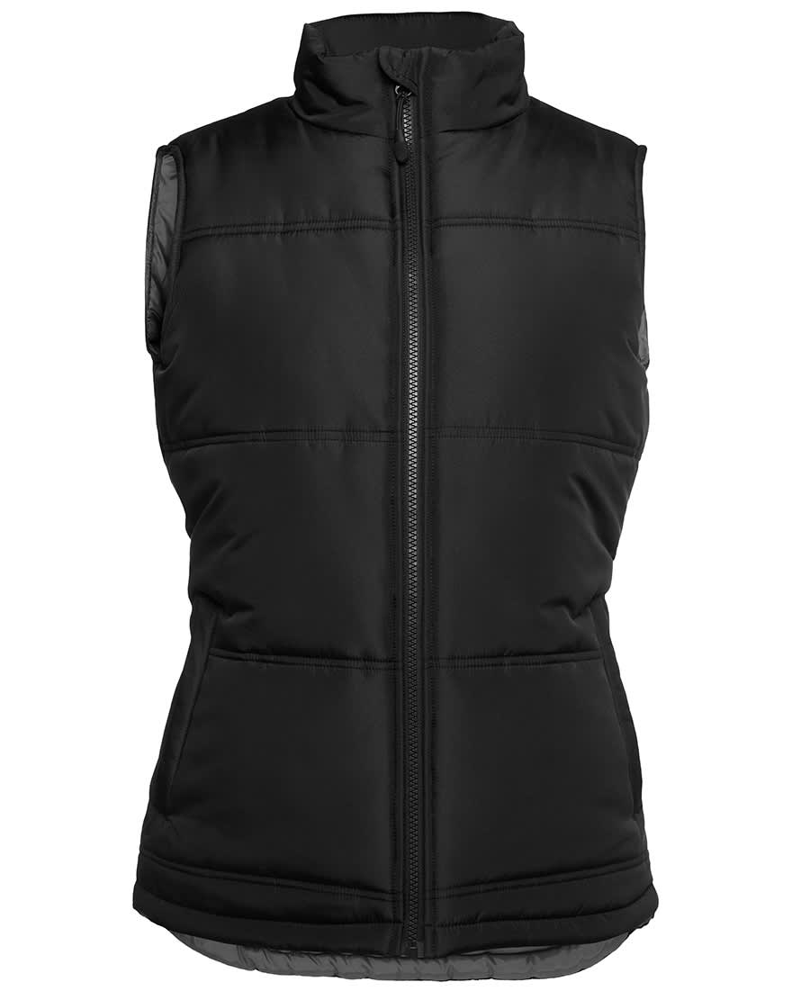 A black puffer vest with a zip front and padded design, featuring side pockets and a high collar. JB's Ladies Adv Puffer Vest - Image 1