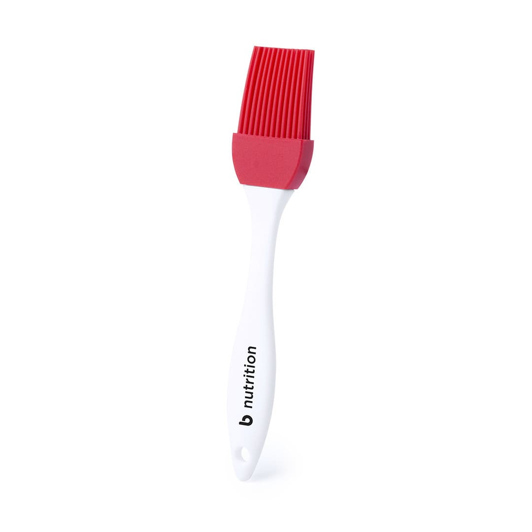 A red silicone brush with a white handle, featuring a logo on the handle. Kolam Brush - Image 1