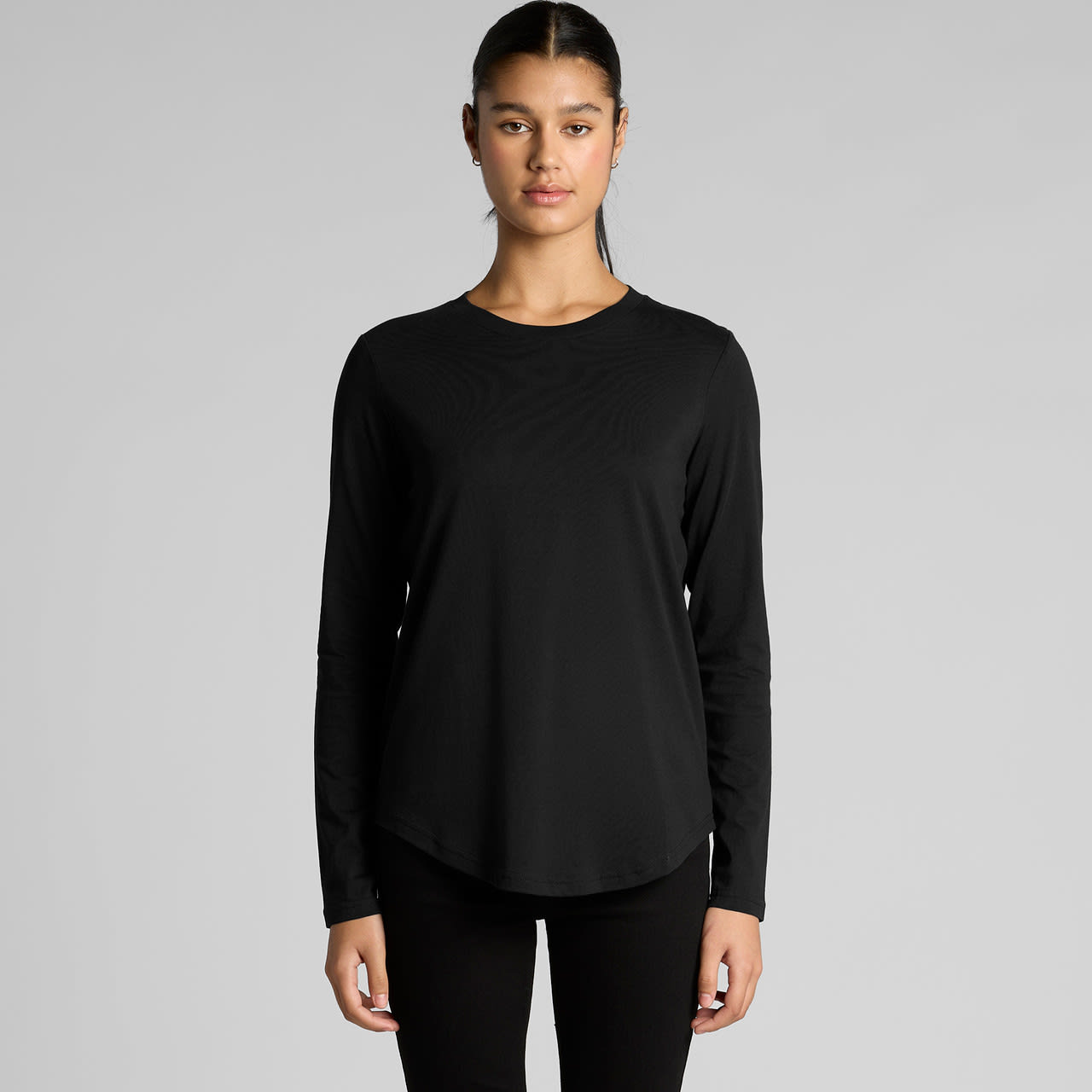 A long-sleeve black t-shirt with a curved hem and a logo. The model is standing front-facing. Wo's Maple Curve L/S Tee - Image 1