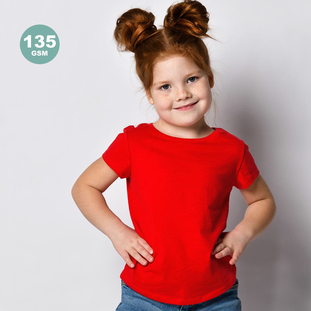 A child wears a bright red t-shirt, smiling with hands on hips, against a plain background. The shirt has a logo. Hecom Kids Colour T-Shirt - Image 1