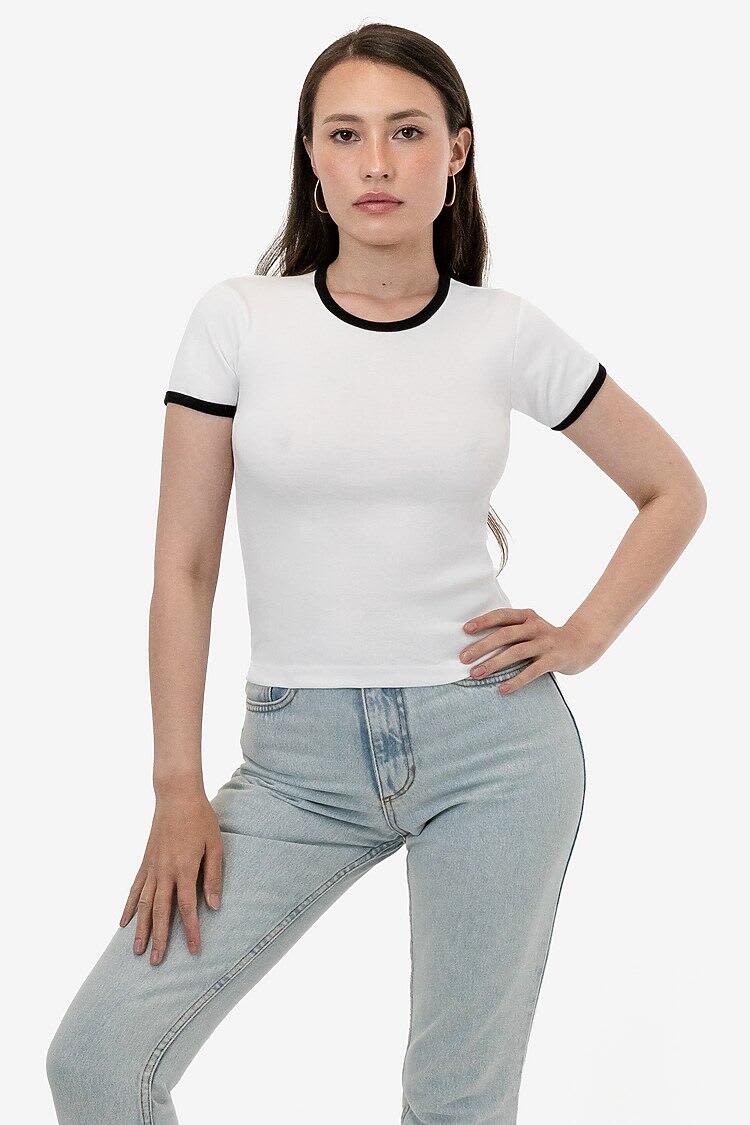 A fitted white baby rib tee with black trim, worn by a model posing in light blue jeans. Original Baby Rib Tee - Image 1