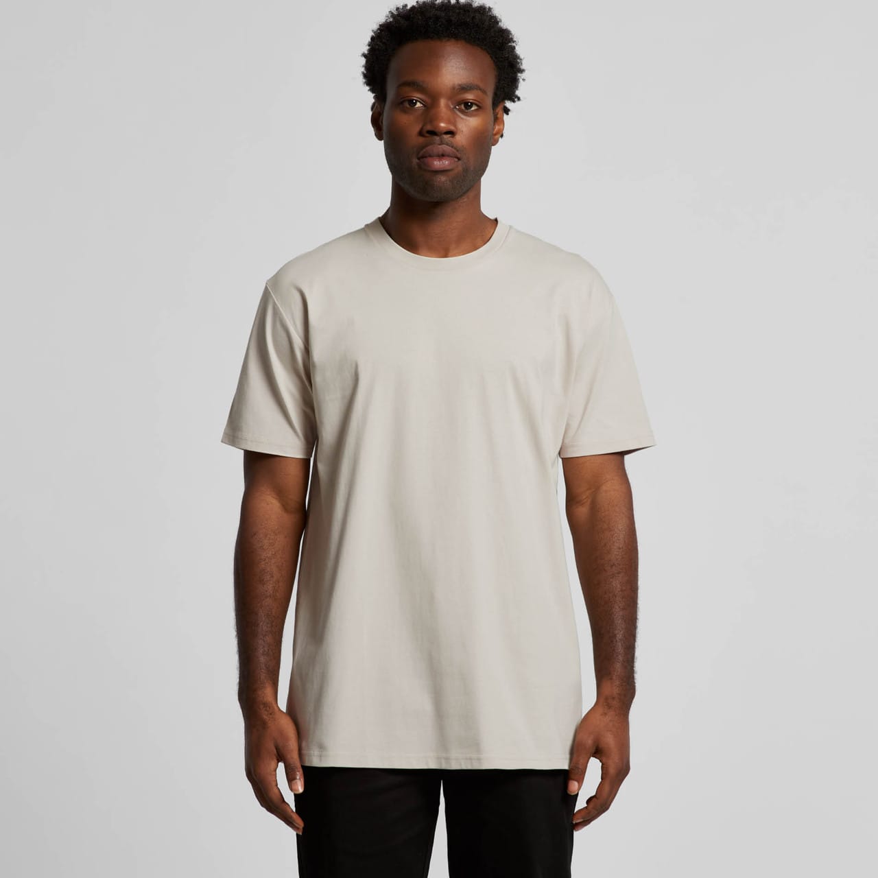 A light beige T-shirt made from soft fabric, featuring a simple design and a round neckline. It has a logo. Staple Tee - Image 1