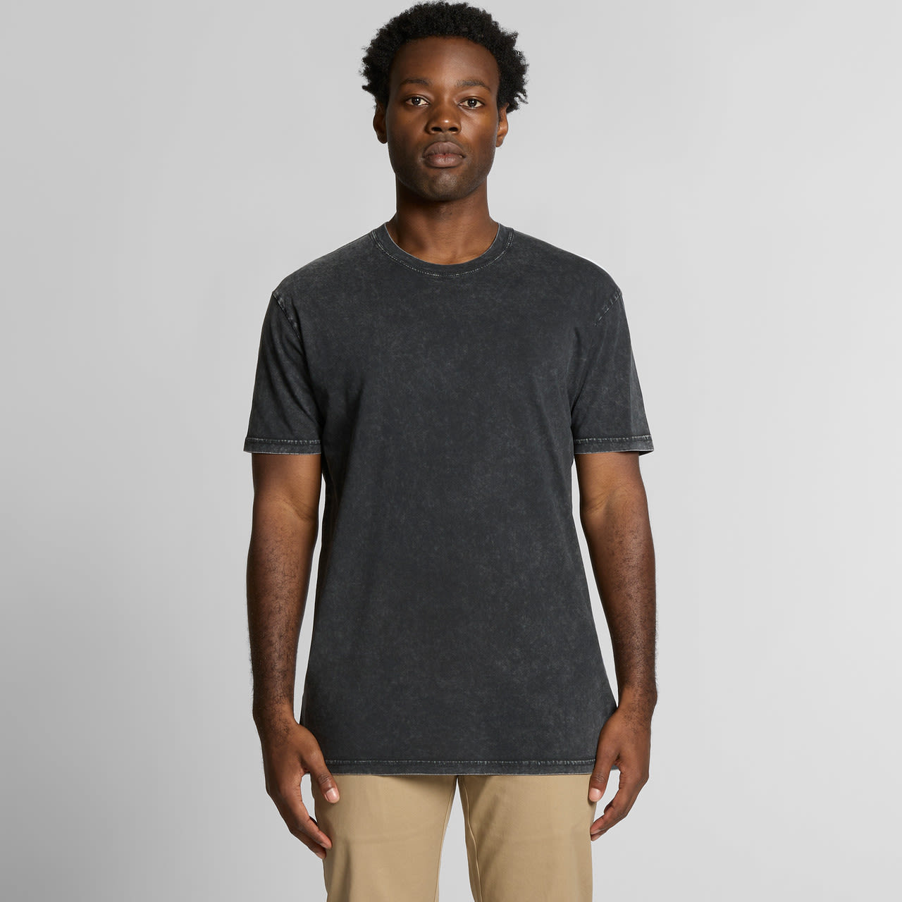 A black stone wash t-shirt featuring a crew neck and short sleeves, displayed on a male model. Staple Stone Wash Tee - Image 1