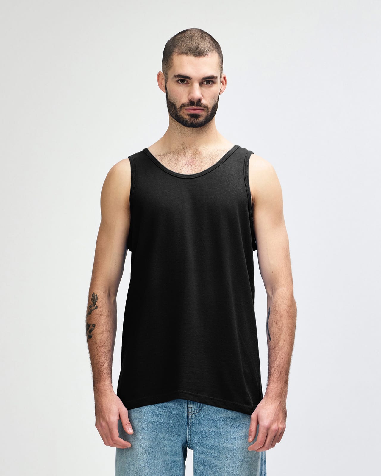 A black Gildan Heavy Cotton adult tank top on a model, featuring a plain design and a logo on the label. Gildan Heavy Cotton Adult Tank Top - Image 1
