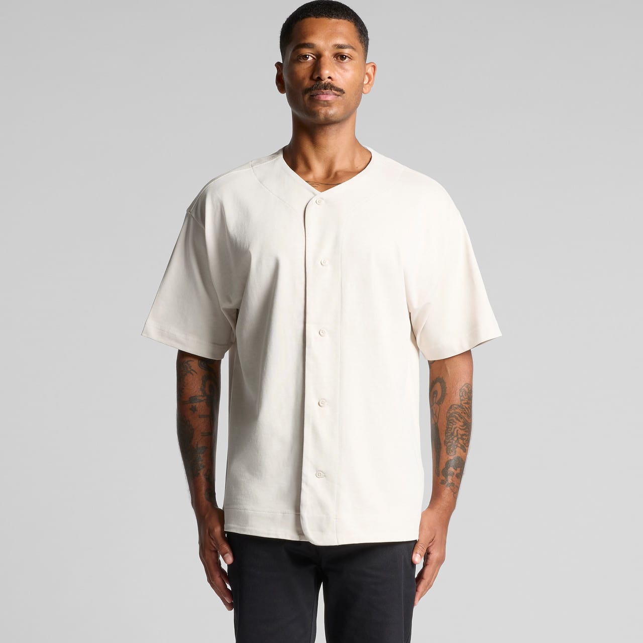 A cream-coloured heavy baseball jersey with short sleeves and a front button closure, featuring a logo. Heavy Baseball Jersey - Image 1