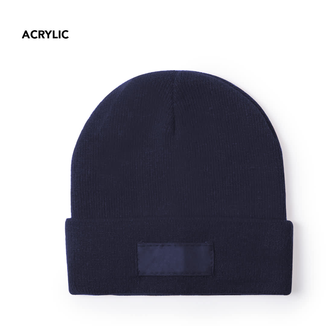 A navy blue beanie with a folded cuff and a patch on the front, made from acrylic material. Holsen Hat - Image 1