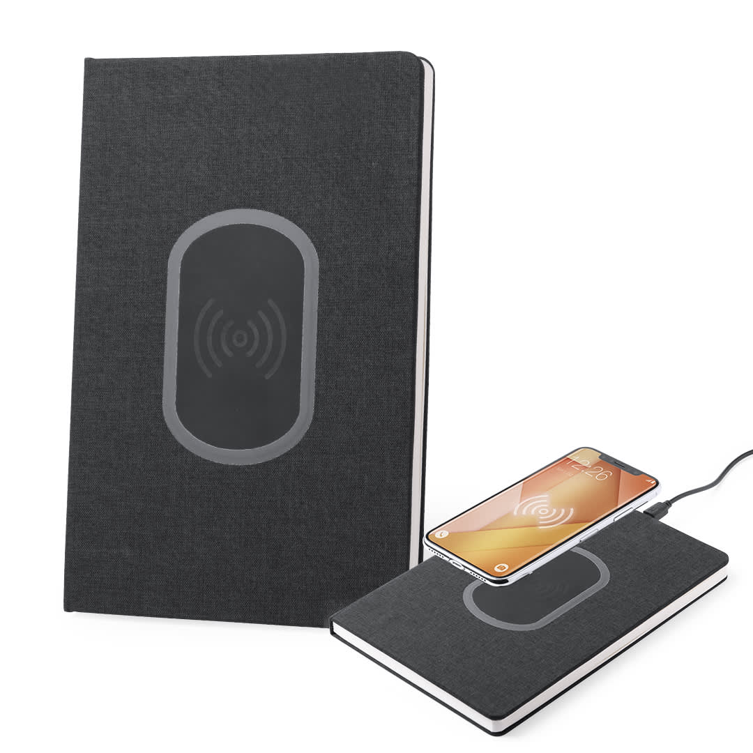 A dark grey notepad with a wireless charging pad integrated on the front, alongside a smartphone charging on it. Kevant Charger Notepad - Image 1