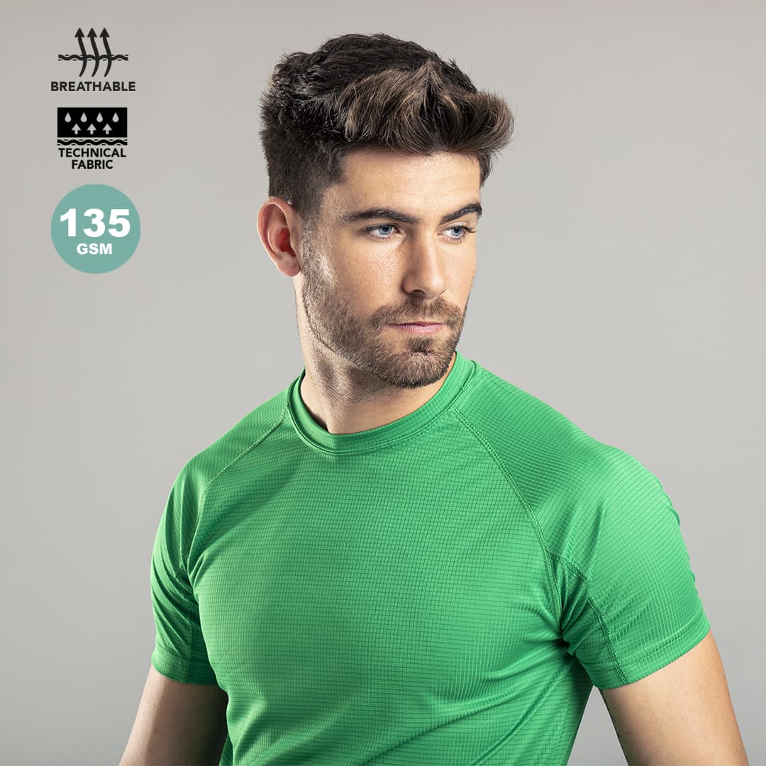 A green adult t-shirt made from breathable technical fabric, featuring a logo and a close-up of a model wearing it. Tecnic Dinamic Adult T-Shirt - Image 1