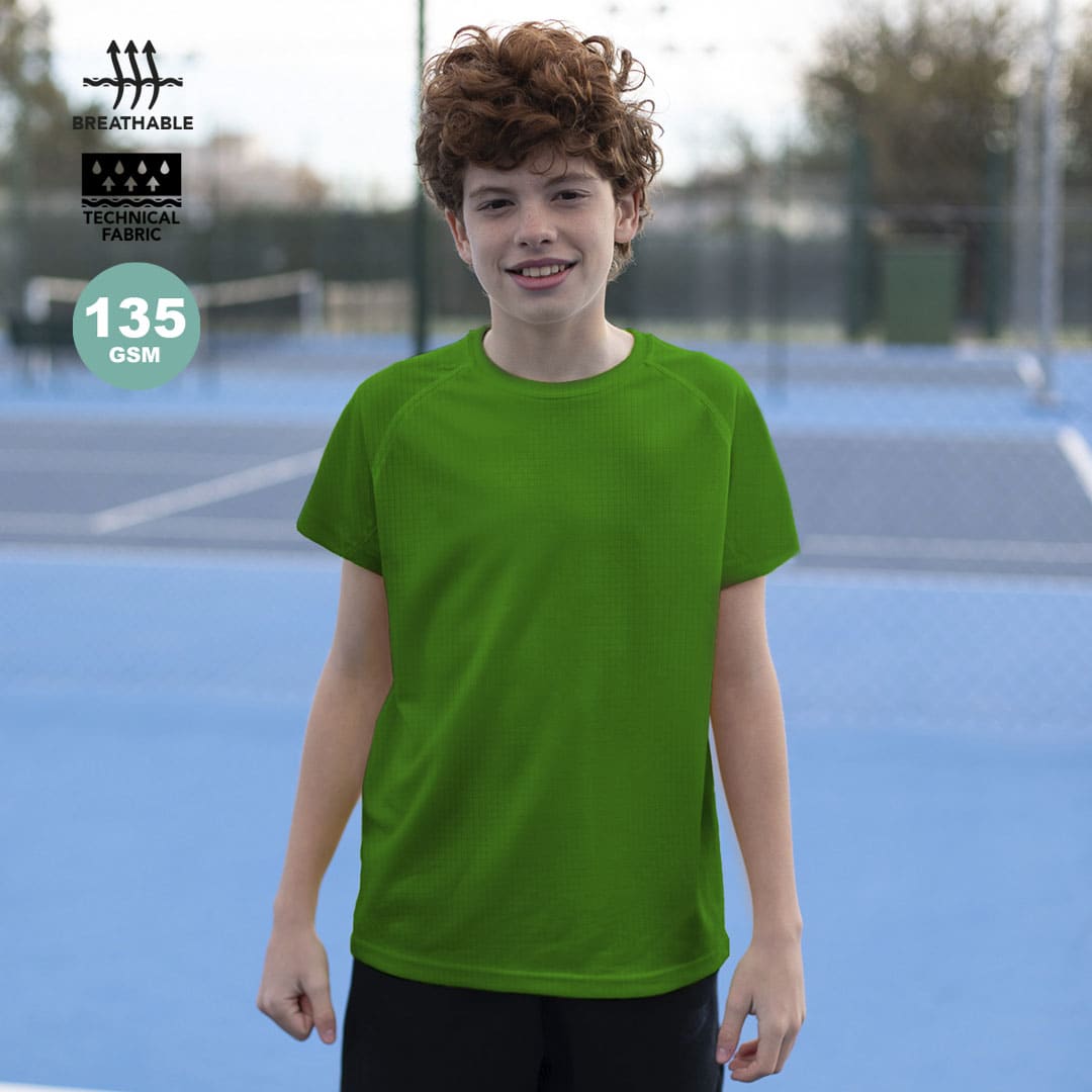A young boy wears a bright green t-shirt, designed with a technical fabric, suitable for active wear. Tecnic Dinamic Kids T-Shirt - Image 1