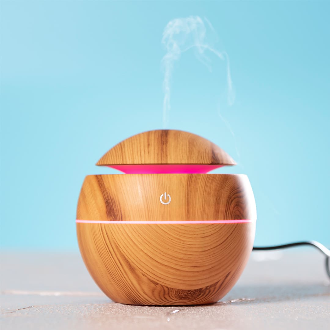 A wooden-looking humidifier with a curved design, featuring a pink light and emitting steam against a blue background. Festok Humidifier - Image 1