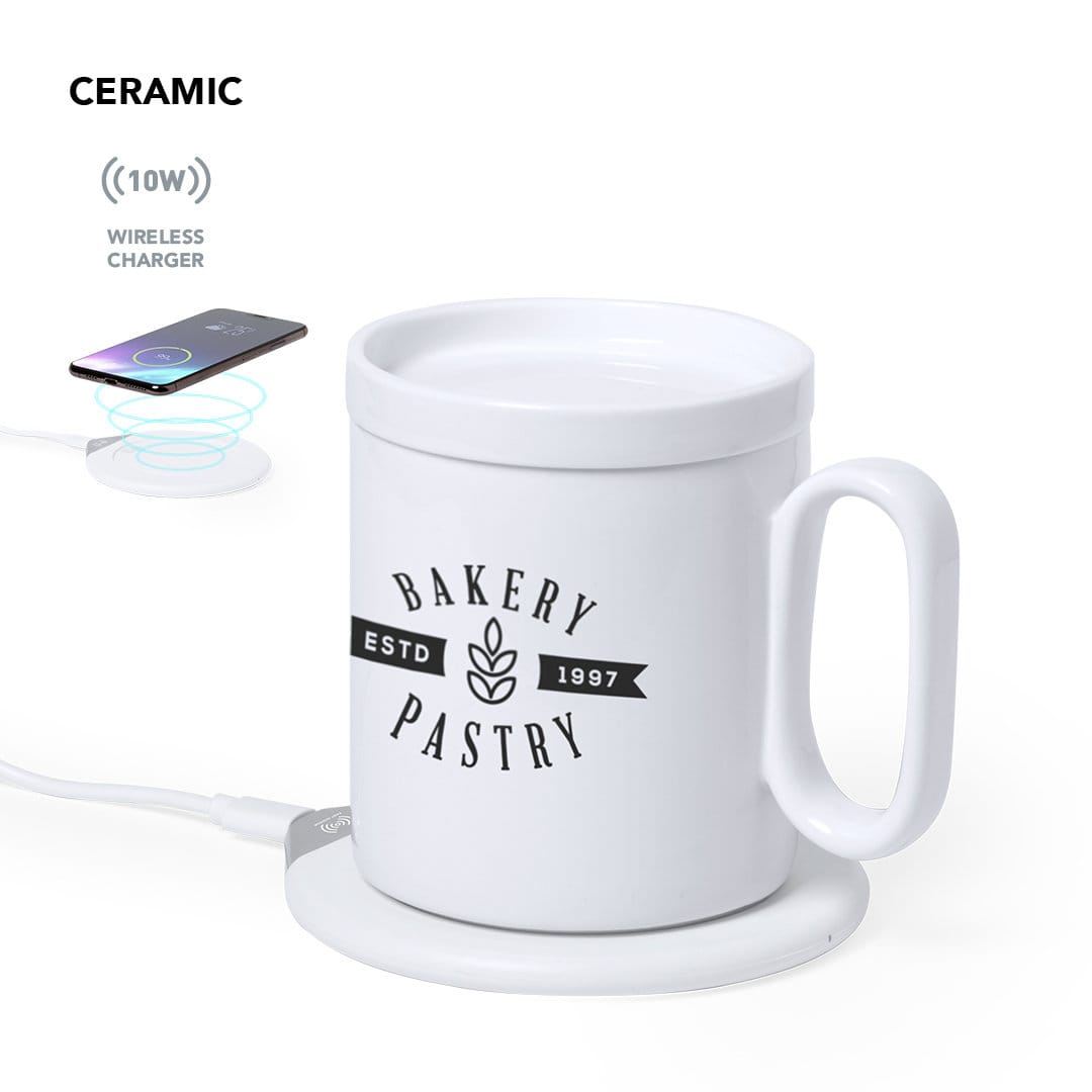 A ceramic drink cup in white with a handle, placed on a round wireless charging base. The cup features a decorative logo. Kalan Charger Cup Warmer - Image 1