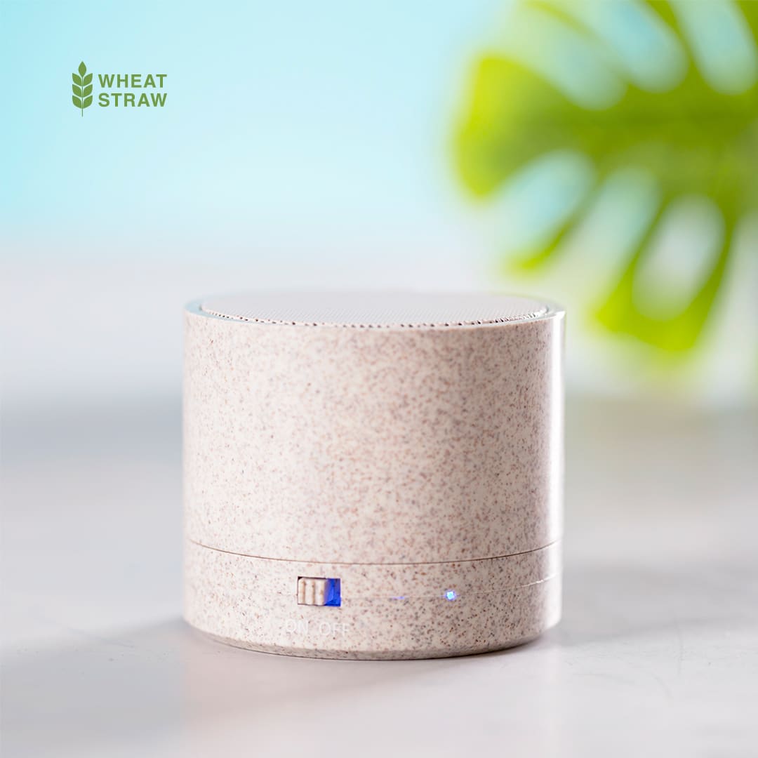 A cylindrical speaker in light beige with a textured finish, featuring a small indicator light and branding. Cayren Speaker - Image 1