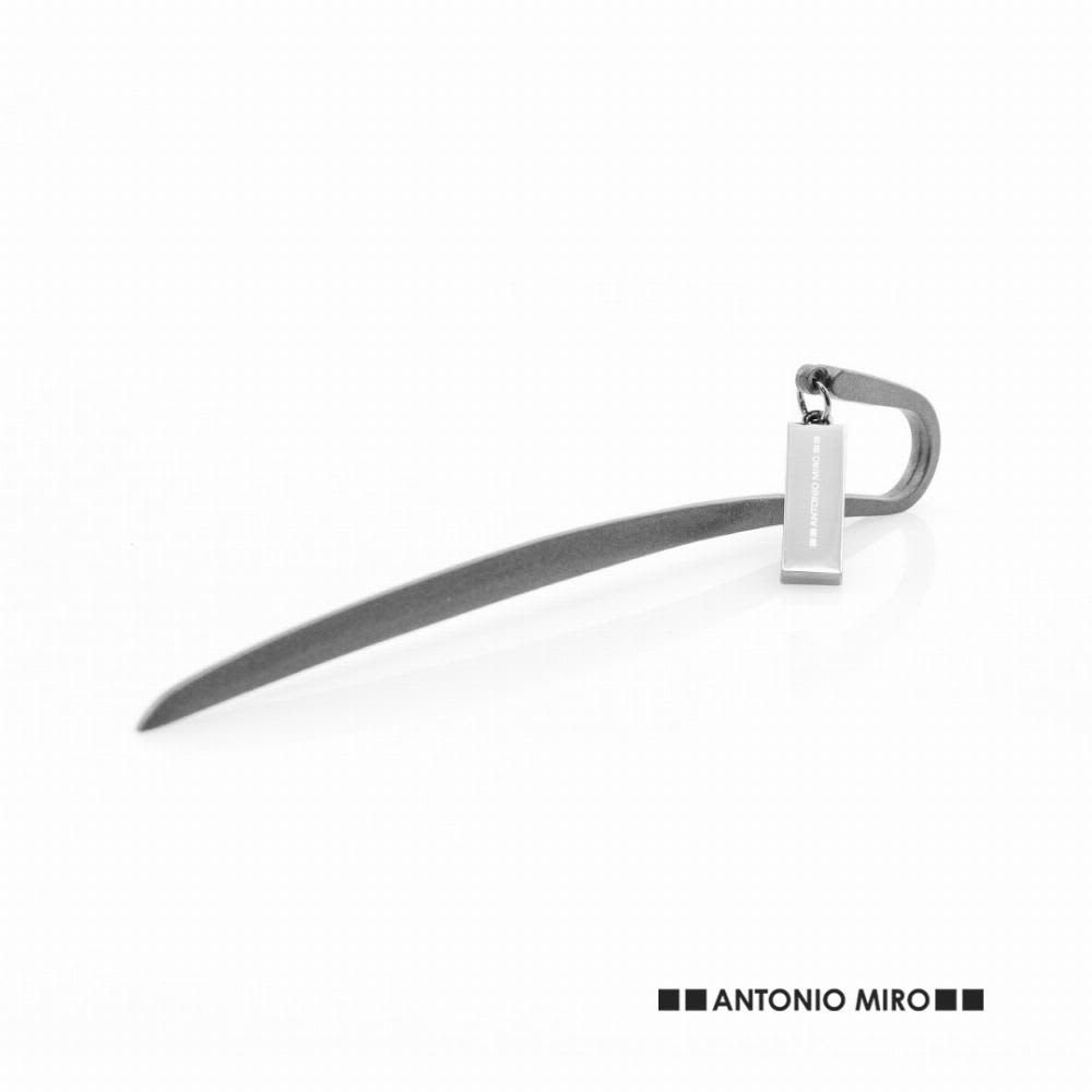 A sleek, silver metal bottle opener with a curved design and an attached tag. Baloa - Image 1