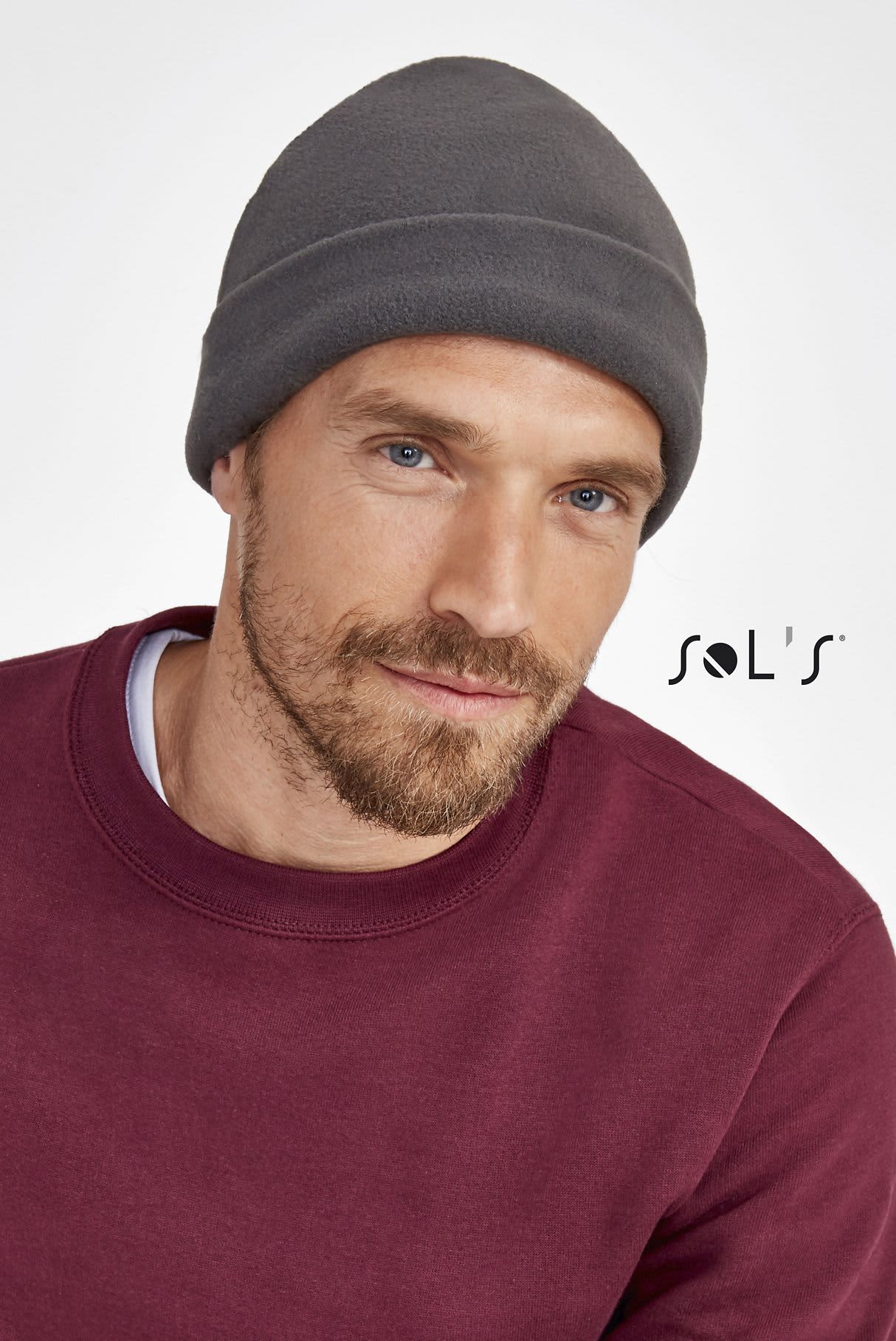 A grey fleece beanie worn by a man with a beard, paired with a maroon sweatshirt. The image features a logo. Beanie 100% polyester fleece SERPICO - Image 1