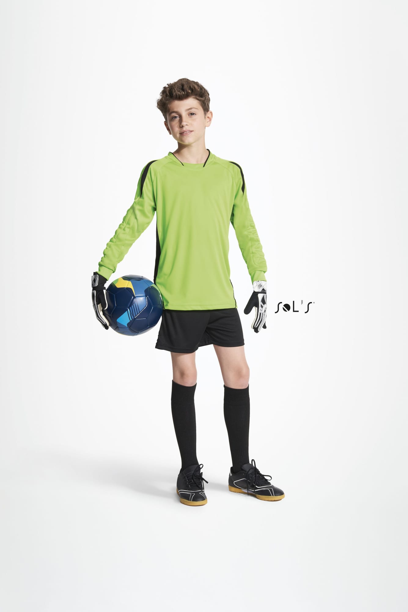 A kid wearing a green goalkeeper shirt, black shorts, and gloves, holding a soccer ball. Soccer GOALKEEPER SHIRT Kids Azteca - Image 1