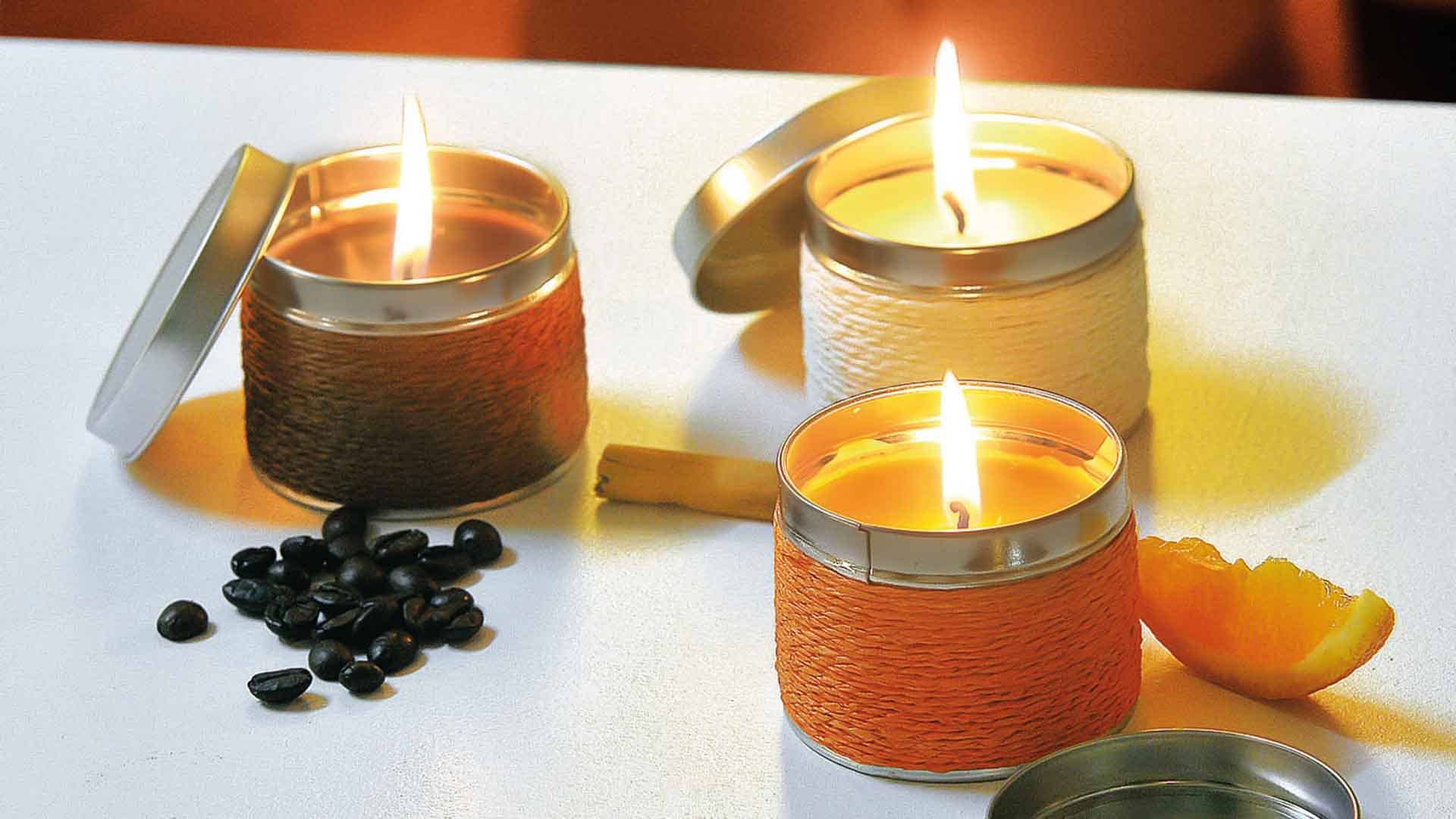 Three scented candles in jars with metal lids, featuring orange, brown, and cream colours, surrounded by coffee beans. Shiva - Image 1