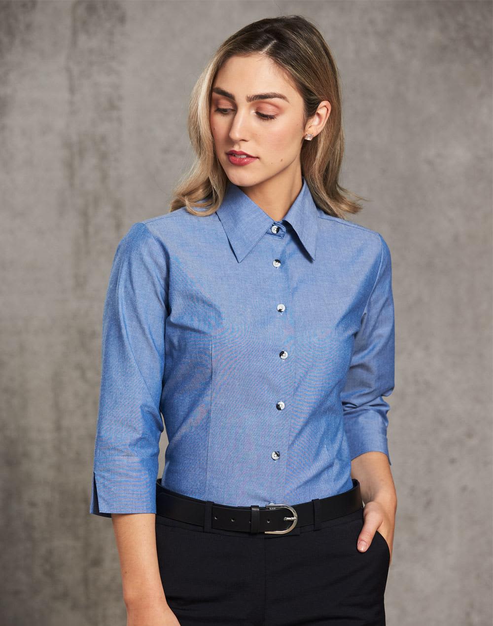 A fitted ladies' chambray shirt in blue with a button-up front and 3/4 sleeves, featuring a simple collar and branding. Ladies' wrinkle free chambray shirt 3/4 sleeve - Image 1