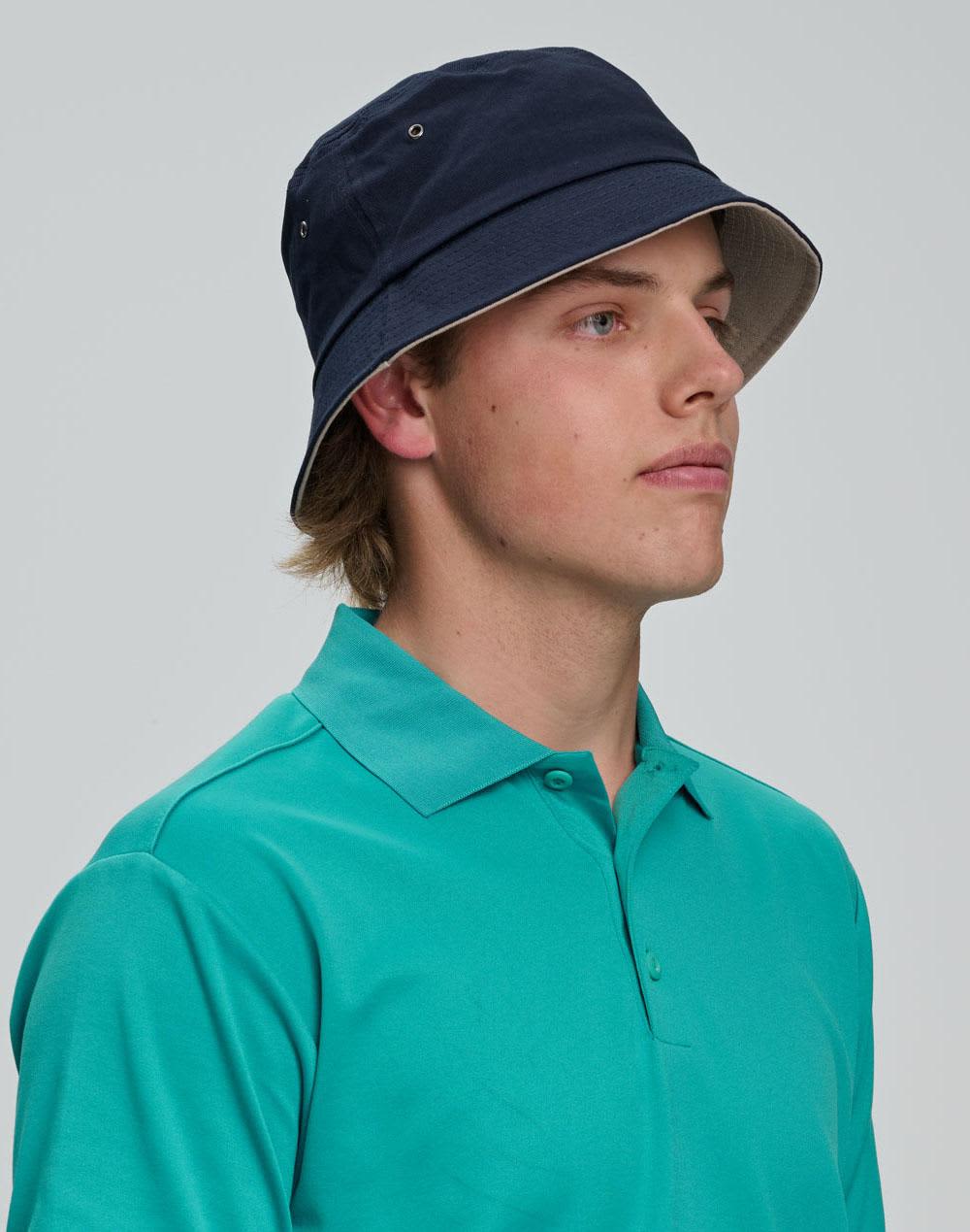 A beige bucket hat with a wide brim and ventilation holes, featuring a logo on the side. contrasting underbrim bucket hat - Image 1