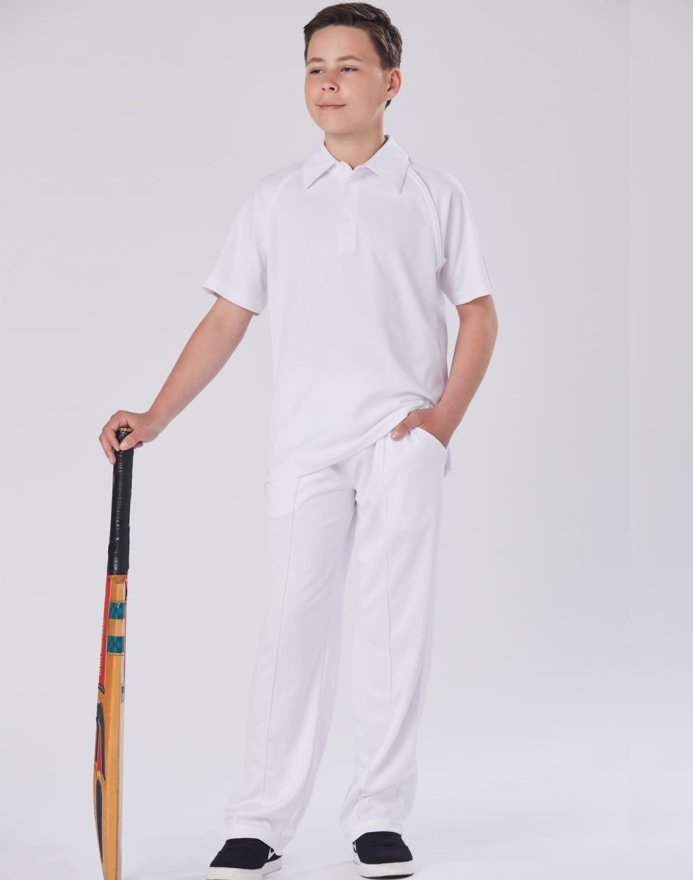 A pair of white kids' cricket pants displayed on a model holding a cricket bat, set against a plain background. Kids cricket pants - Image 1