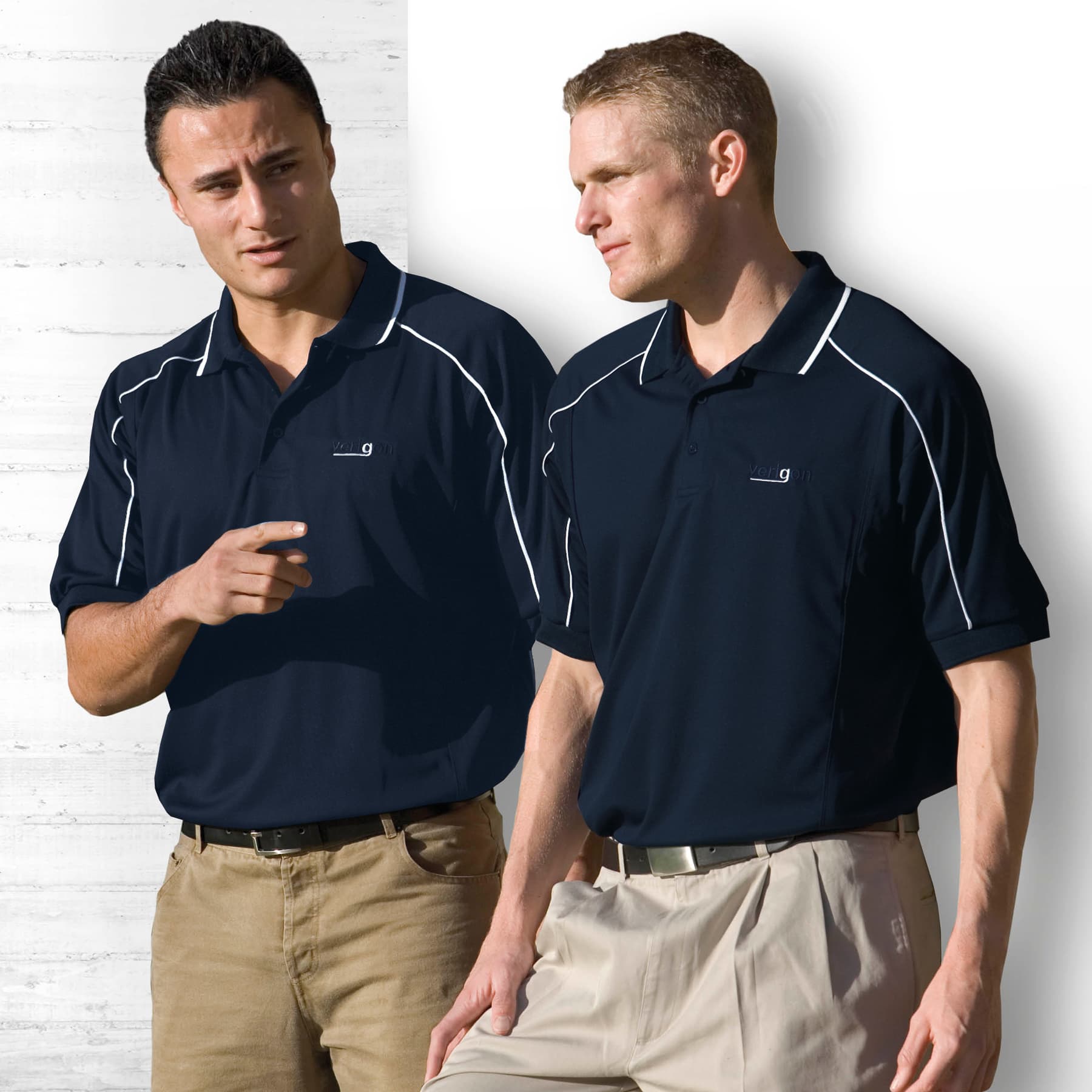 Two men wearing navy blue Dri Gear Eyelet Polo shirts with white detailing and logos, standing against a light background. Dri Gear Eyelet Polo - Mens - Image 1