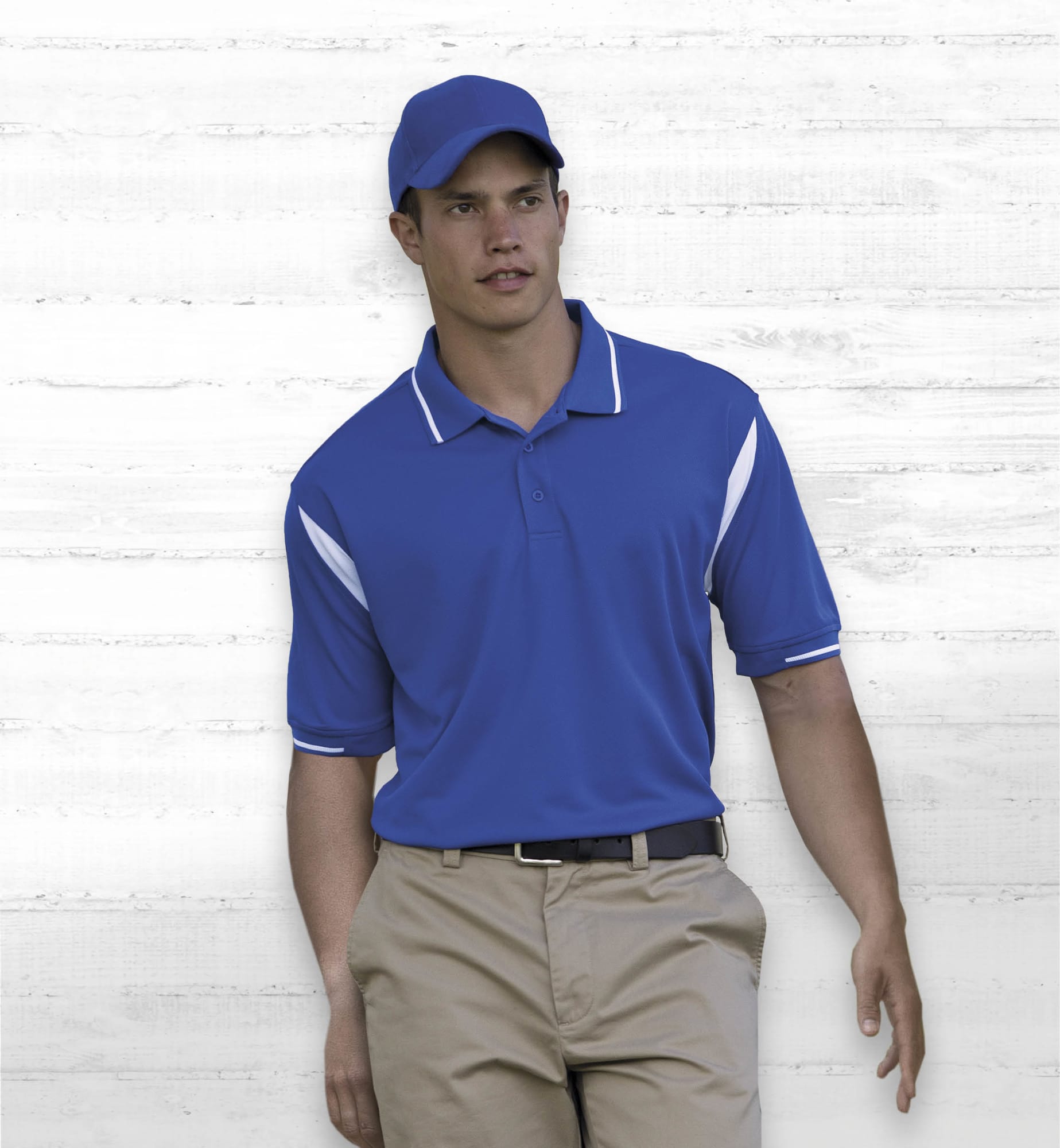 A blue polo shirt with white accents, worn by a model and complemented by a blue cap. The shirt features a logo. Dri Gear Insert Polo - Image 1